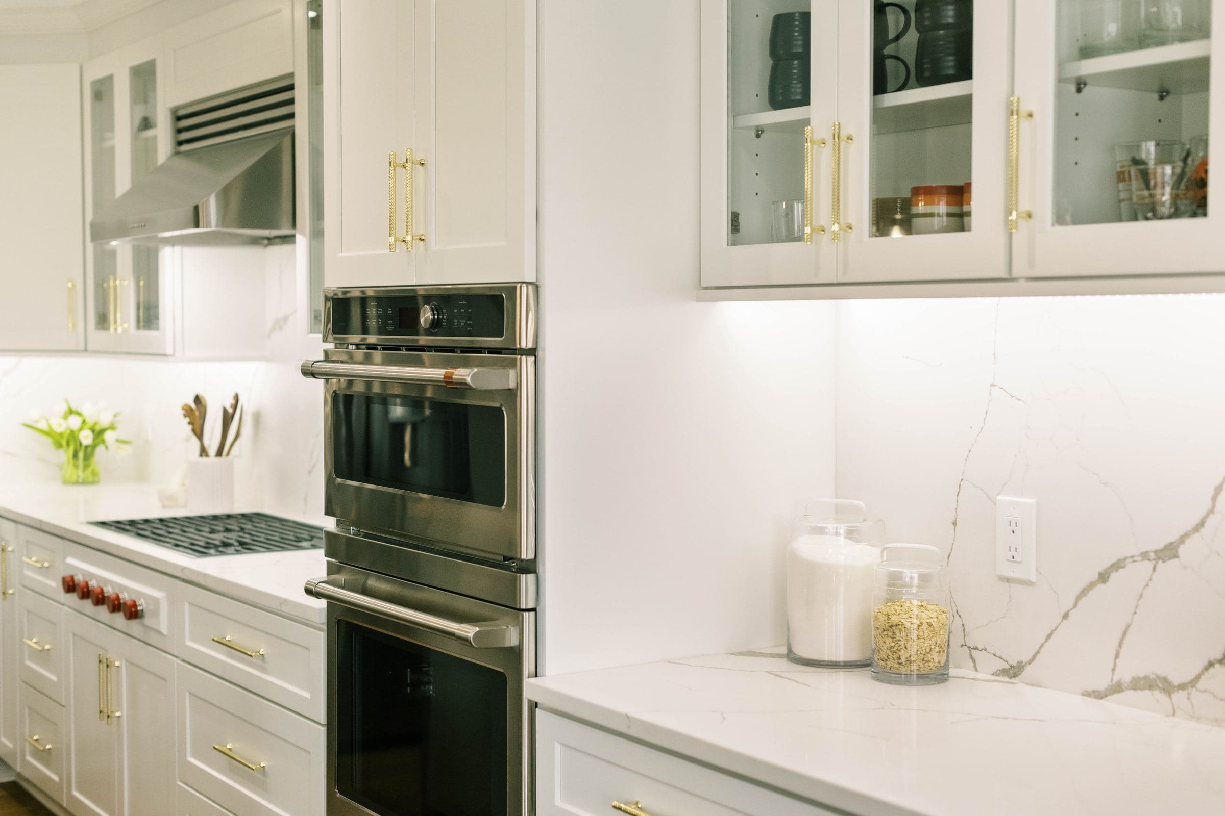 White kitchen with double wall ovens and glass-front upper cabinets