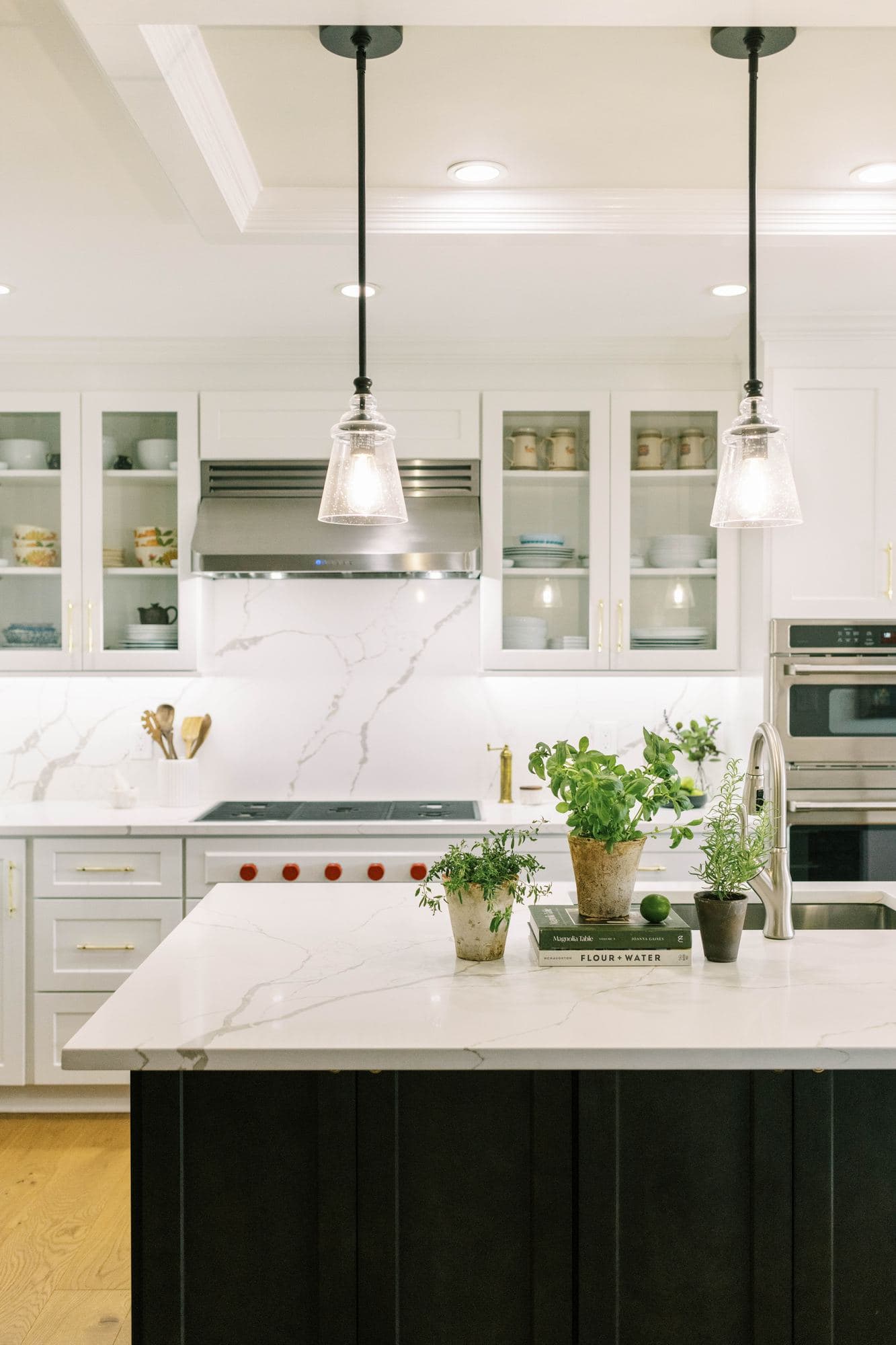 Dark painted kitchen island with pendants and a veined countertop